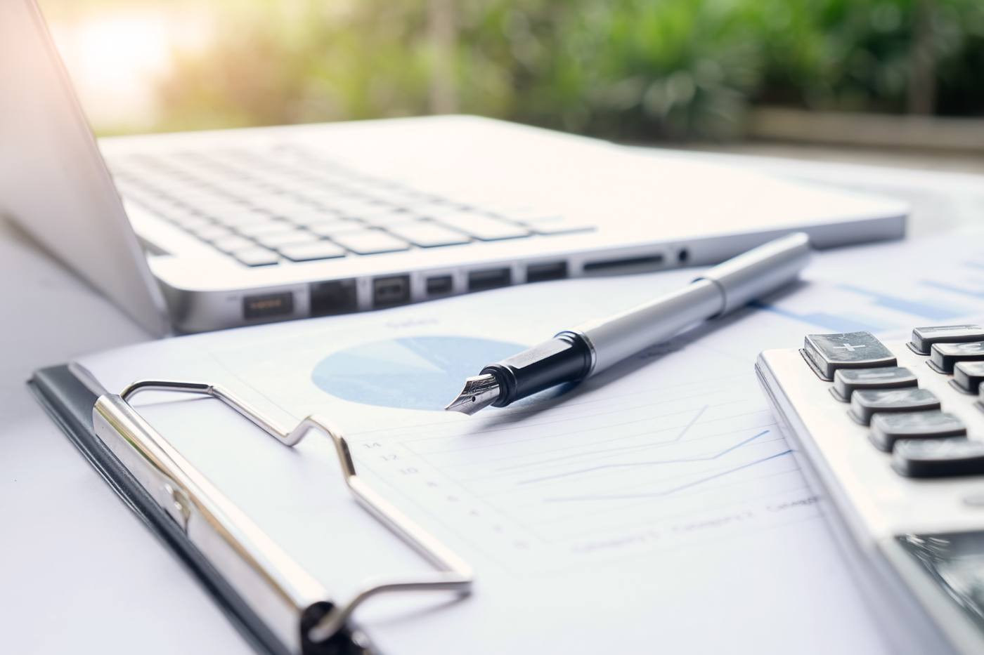 Účetní dokumenty, grafy, kalkulačka a notebook na pracovním stole